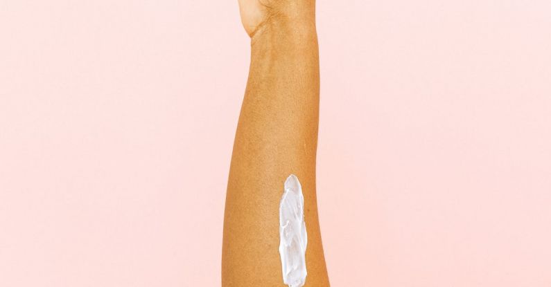 Therapy - Female arm with smear for skin care against pink background
